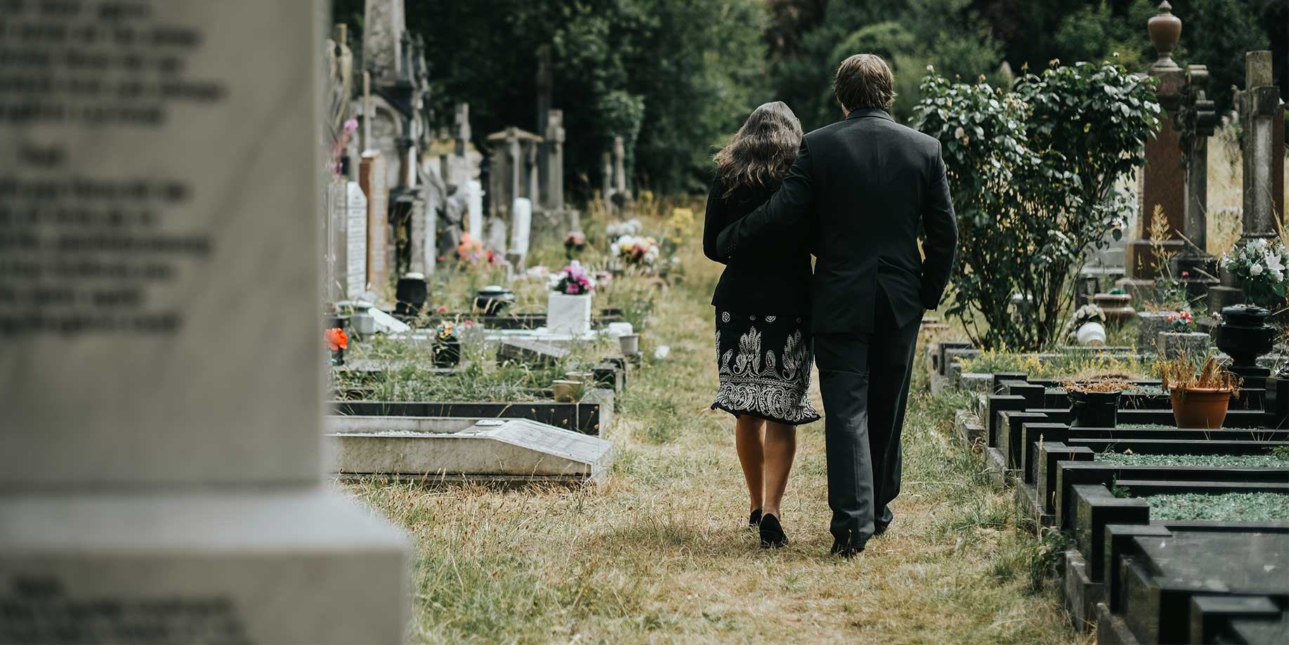 Couple supporting each other while walking through a cemetary