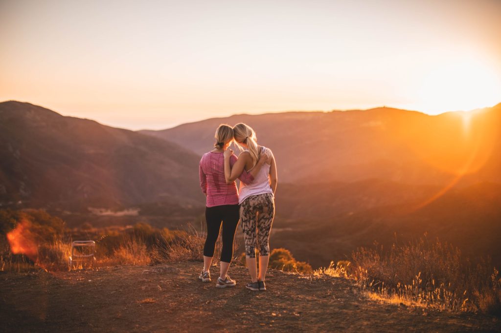 Two women in sports clothing hugging looking at the horizon