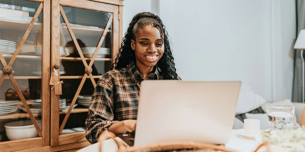 A smiling woman working on her fundraiser using a laptop