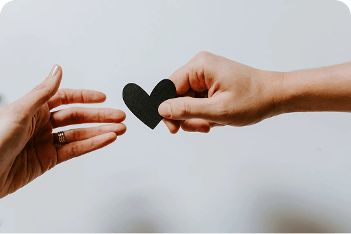 A hand handing a heart to another hand